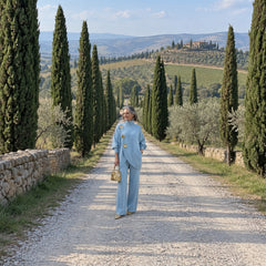 Carolina completo in maglia azzurro, donna su una strada di cipressi in Toscana, vista intera