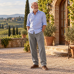 Corrado pantaloni in velluto a coste grigio – uomo con camicia azzurra davanti a una villa toscana